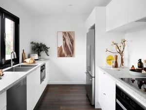 Kitchen with white cabinets and grey benchtops.