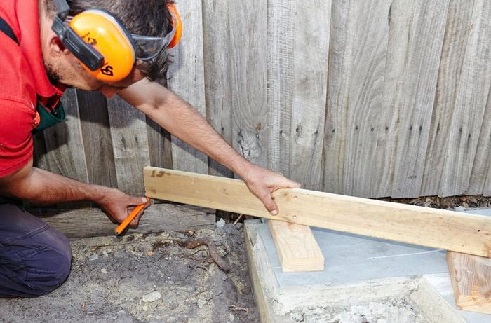Person holding timber and marking it with a pencil.