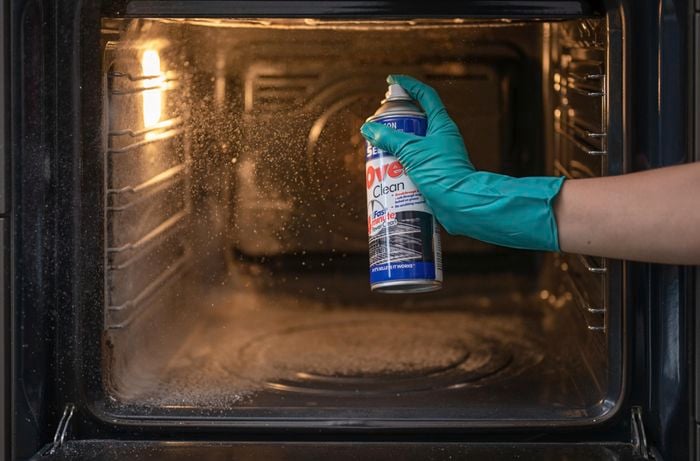 Spraying over cleaner inside the oven.