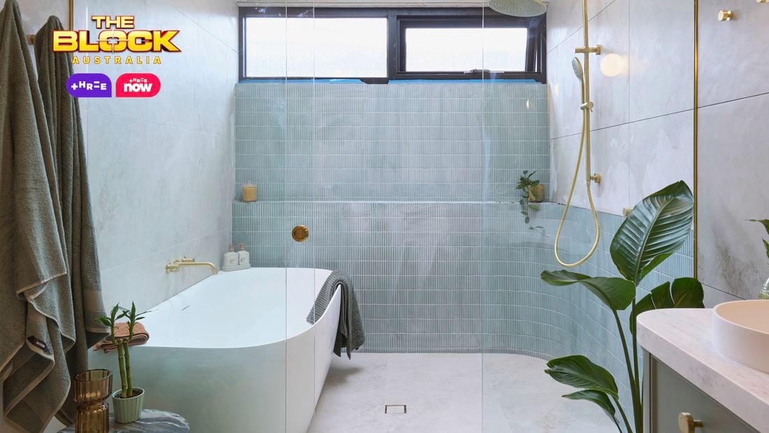 Green, gold and white coloured bathroom with a timber fluted profile vanity and marble benchtop and bath in it.