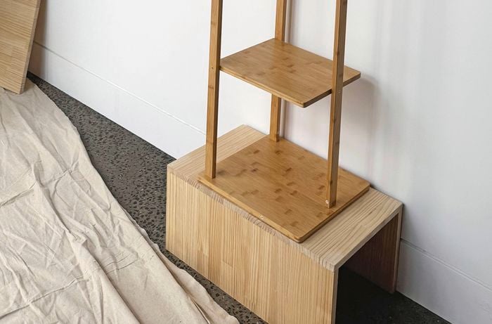 Close up of a timber plinth with a coat rack sitting on top.