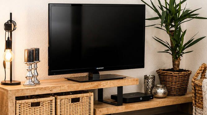 TV unit featuring a timber-look finish with black metal supports, styled with baskets, decorative accessories and a flat-screen television.