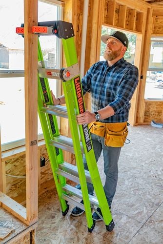Man leaning ladder against timber wall frame