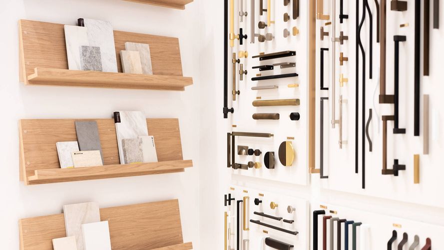 Design selection wall featuring cabinet handles, hardware finishes and material samples displayed alongside timber shelving.