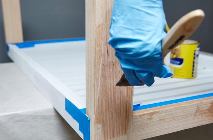 Person applying varnish to table leg