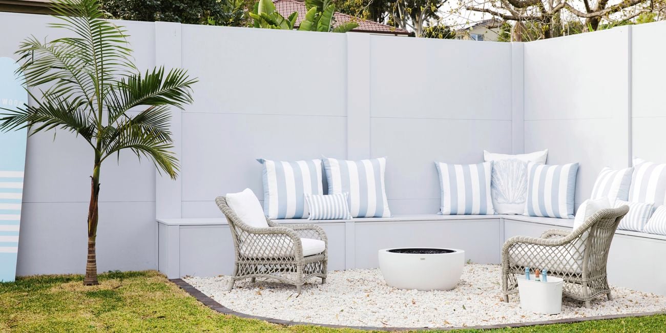 Outdoor lounge area with chairs, table and bench with pillows