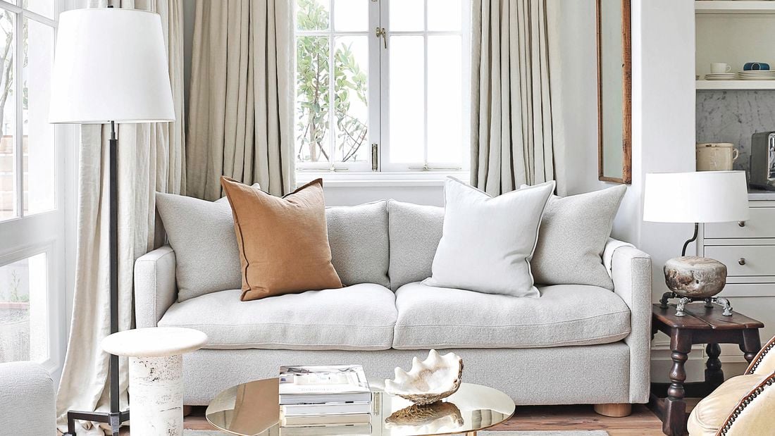 Living room with grey interior theme, a patterned grey rug with couch on top and two lamps beside the couch.