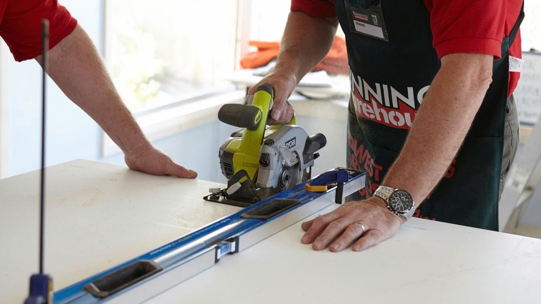 A person cutting a laminated benchtop with a saw