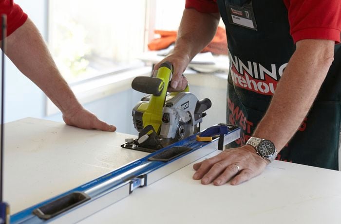 A person cutting a laminated benchtop with a saw