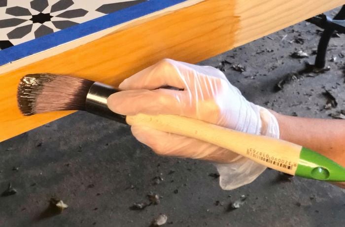 Timber stain brushed onto the frame of a tiled table