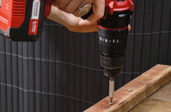 A wooden benchtop being fixed together with screws and a power drill
