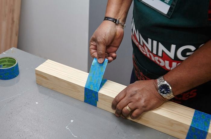 A person taping lengths of pine timber together