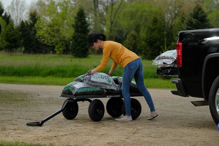 Woman loading cart with bags of fertiliser