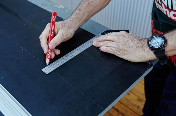 A square rule and pencil being used to mark spaces for plant pots to sit in a hanging garden tier