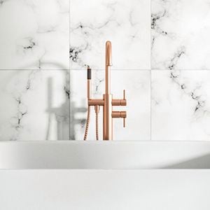 Bath with gold tapware and marble floor and wall