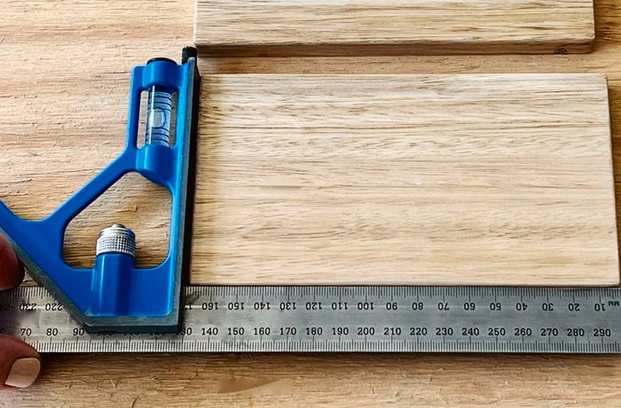 A person uses a combination square to measure pieces of DAR tasmanian oak timber.