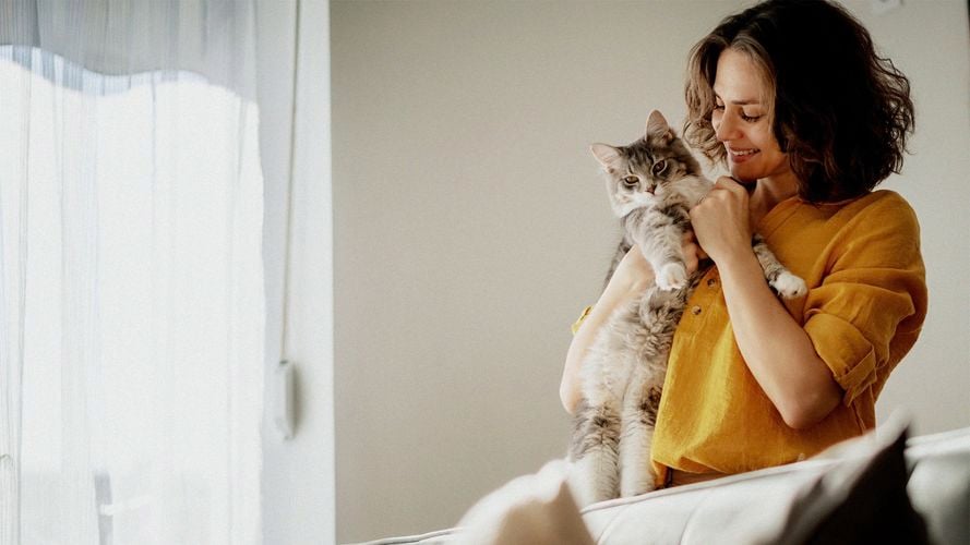 A woman holding a cat close to her.