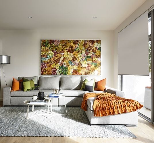 A vibrant lounge setting with couch, rug and large colourful wall hanging