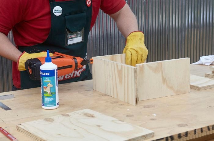 Person using nail gun to nail piece of timber together