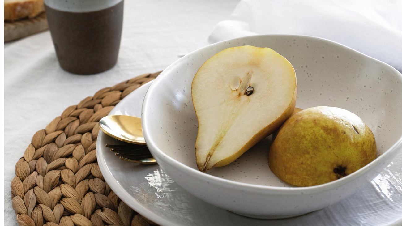 Pear halves in a bowl next to a coffee cup.
