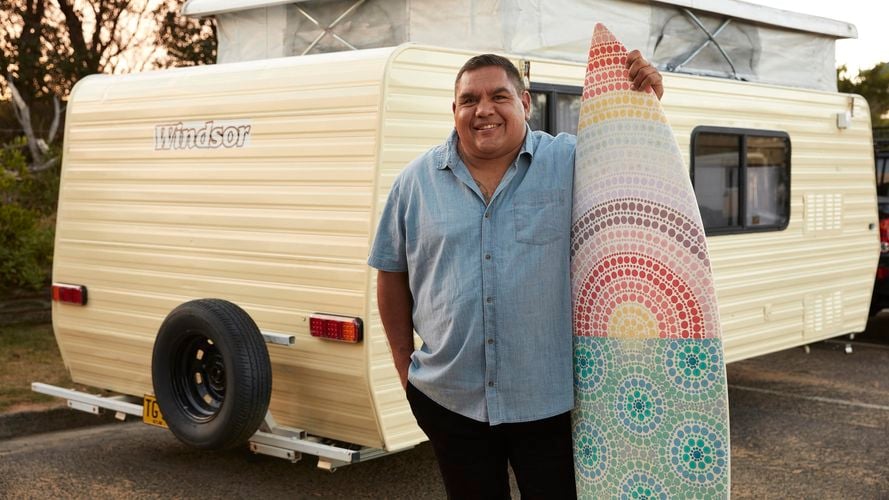Man stands next to his surfboard customised with Coloursmith