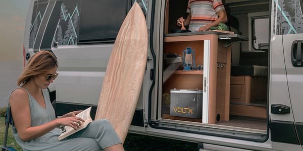 VoltX battery powering a campervan with woman reading and man making food in kitchen.