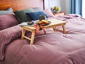Bed with tray table on it with breakfast items.