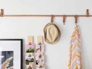 Hat and towel hanging on hooks attached to dowel on a white wall