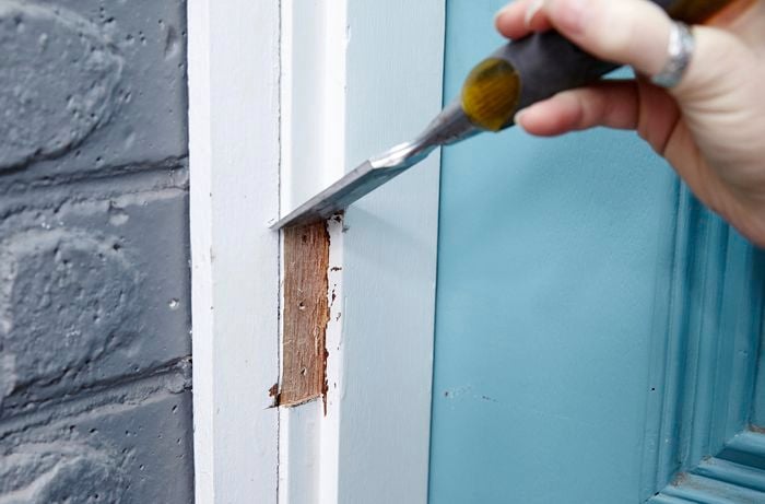 A chisel being used to square up the door frame's door jamb