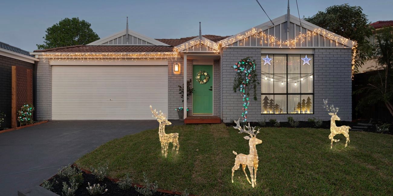 Front of house with fairy lights, Christmas decorations in the window and lit up reindeers.