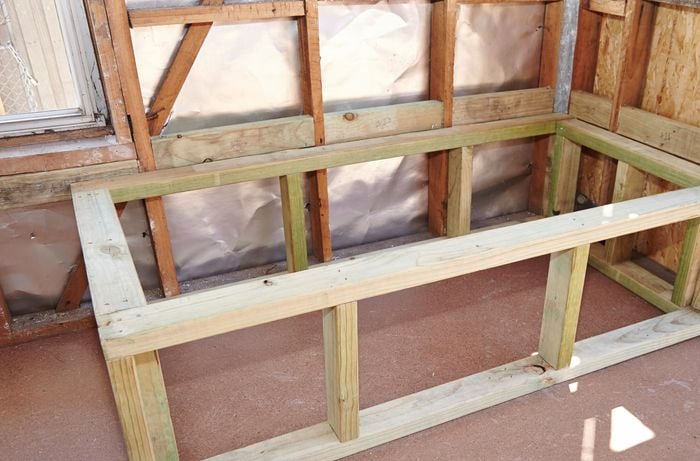 A finished timber bath frame in the corner of a bathroom with exposed stud walls