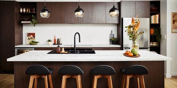 Mid Century Modern kitchen with dark wood cabinets, marble island, and retro pendant lights
