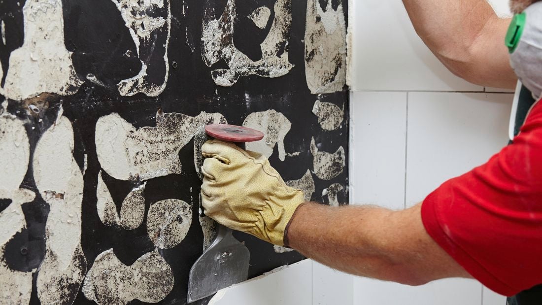 A Bunnings team member removing tiles from a wall with a mash hammer and brick bolster