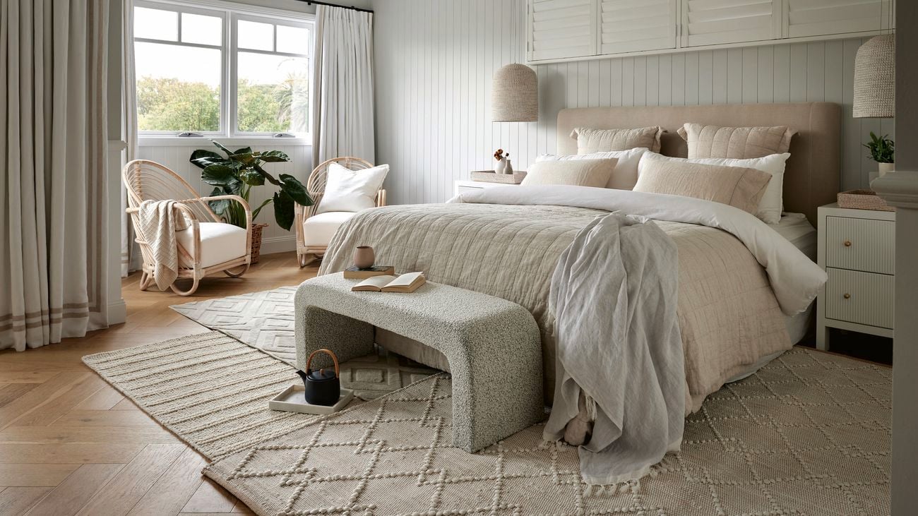 Shot of a cream-coloured room with carpets and fresh bedding.