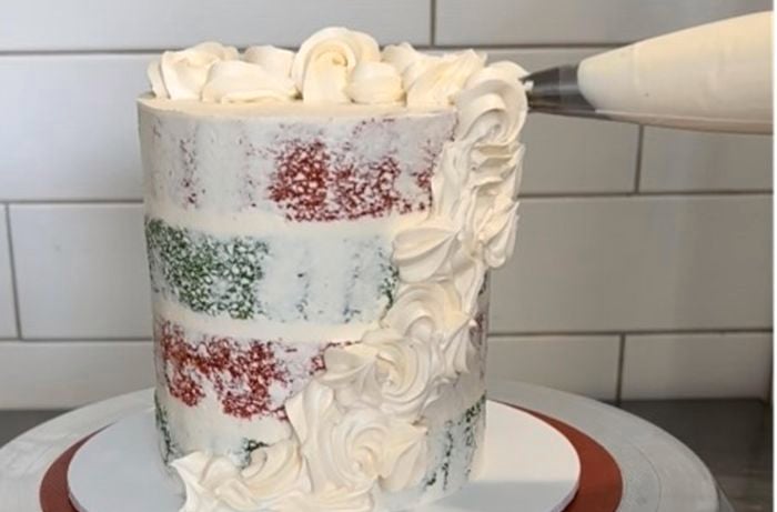 birthday sponge cake been decorated with white icing from a piping bag