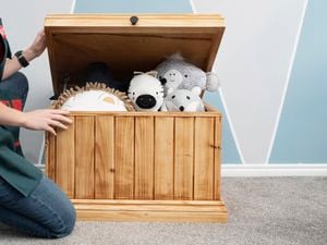 Woman opening a wooden toybox full of children's toys