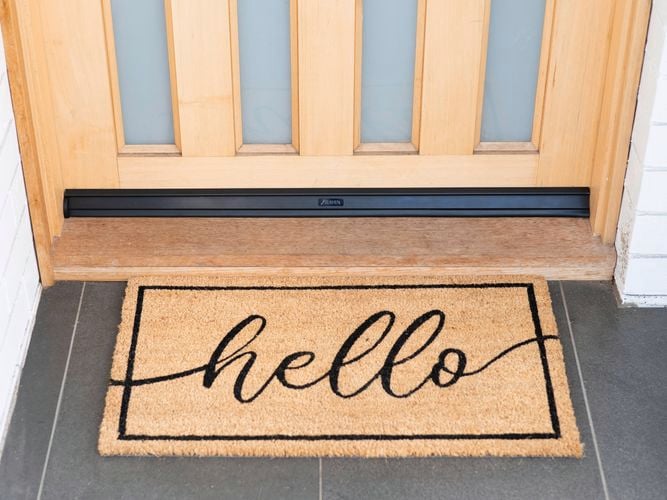 Front door with a doormat featuring the word "Hello".