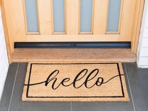 Front door with a doormat featuring the word "Hello".