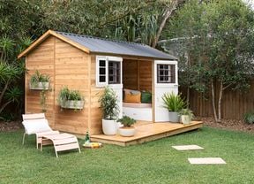 A timber garden shed and garden furniture in a backyard