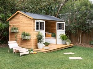 A timber garden shed and garden furniture in a backyard