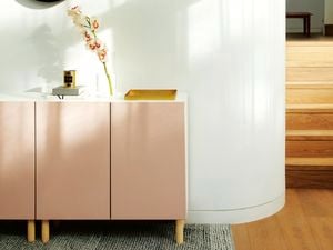 White buffet unit with dusty pink doors against a white wall