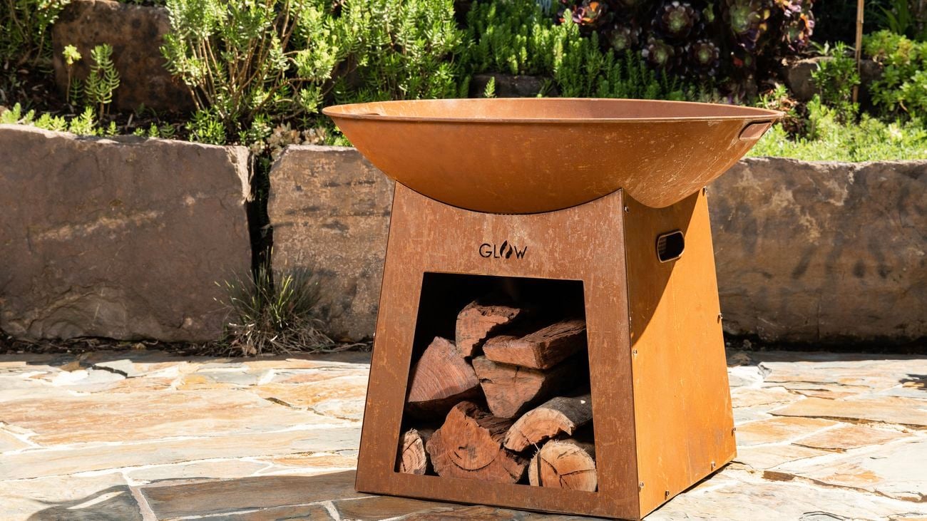 Brown Tambo fire pit in backyard, unlit with logs stacked inside