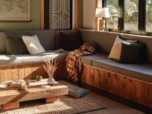 <p>Grey couch with grey curtains by the open window in a living room. Other furnishings like a coffee table, a white lamp and a large window are also featured</p>