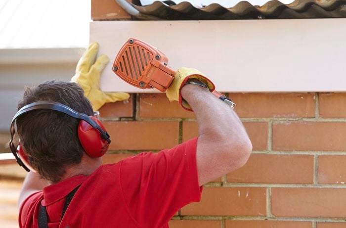 A person attaching a length of fascia using a nail gun