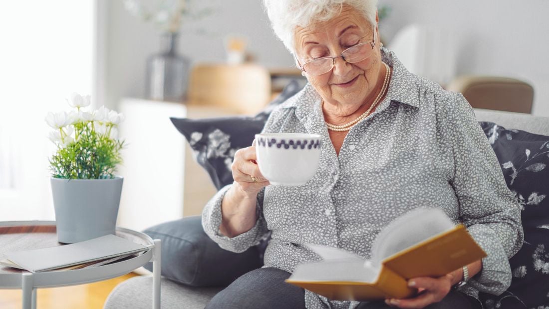 Person reading a book and drinking a tea.