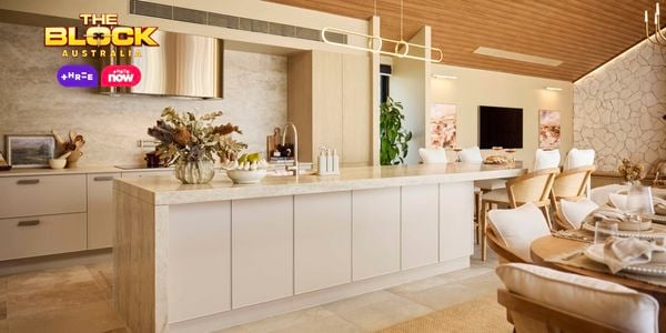 Modern kitchen with marble island, stone feature wall, and dining table.