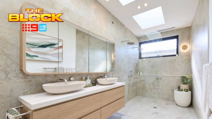 A furnished modern bathroom with two basins on drawers, a shower, window, skylights, mirrors on the wall in it.