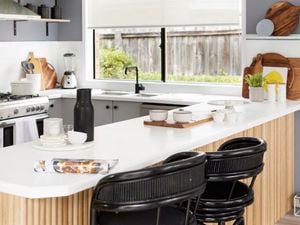 Kitchen benchtop with chairs and an oven in a kitchen