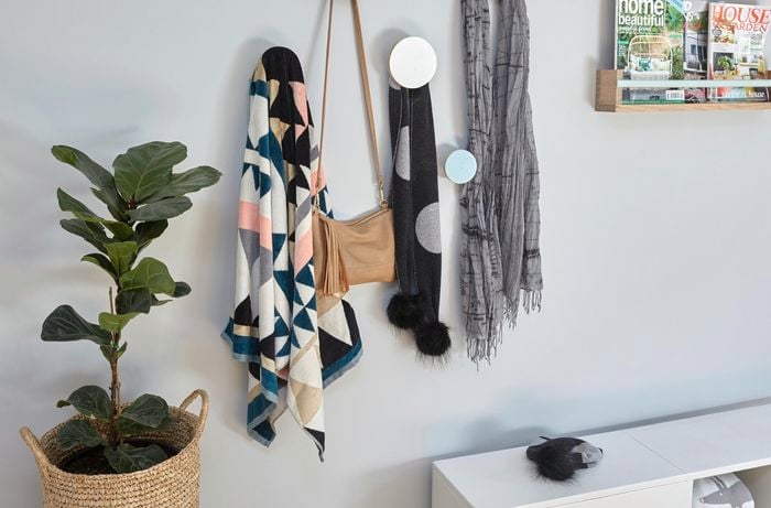 Clothing and bags hanging on round hooks on a bedroom wall