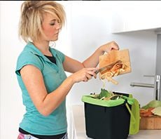 Woman scraping food scraps into small food scrap bin